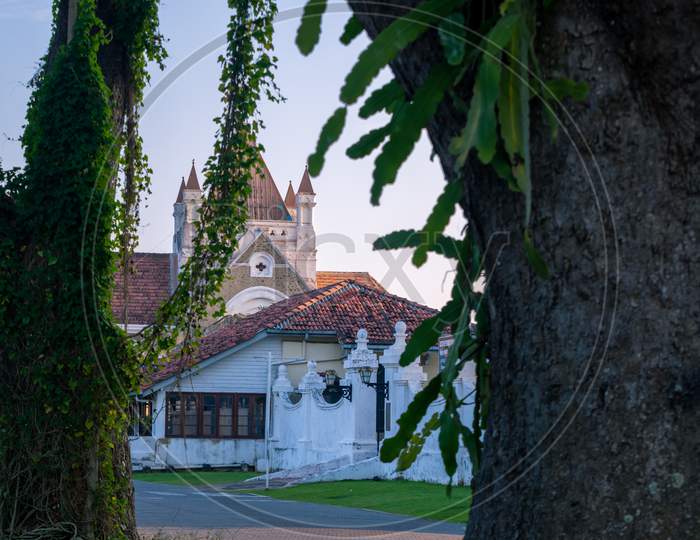 All Saints Church And Galle Fort Library In The Distance View Between Tall Trees In The Evening.