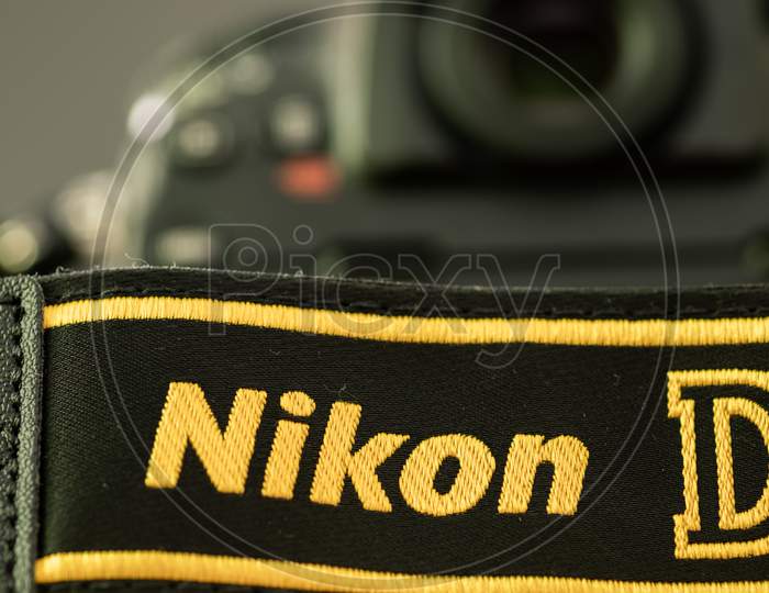 Galle, Sri Lanka - 02 17 2021: Nikon D Series Dslr And Camera Strap On Wooden Table Close Up, Brand New Nikon Logo Embroidered In Yellow Into A Black Ribbon, Professional Factory Finishing Product.