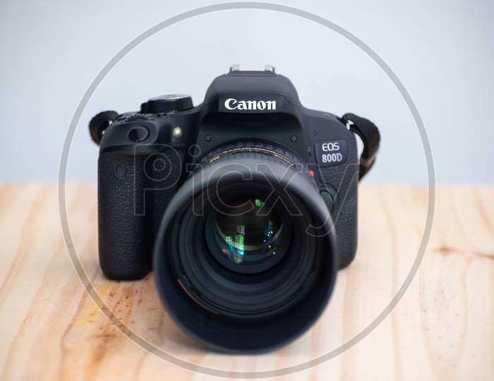 Galle, Sri Lanka - 02 18 2021: Canon Eos 800D Also Known As Rebel T7I Dslr Camera And The Mounted Tokina 100Mm 2.8 Macro Lens With Lens Cap Front View, On A Wooden Table, Neutral Color Background.