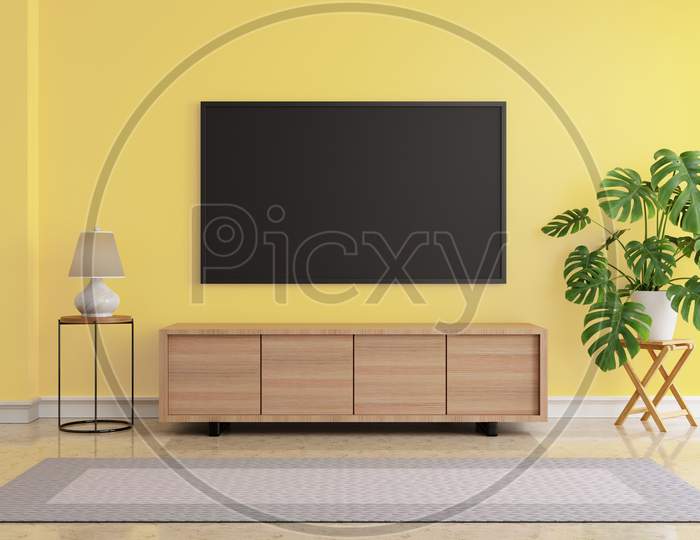 Living Room With Blank Screen Hanging Lcd Television Mock Up On Yellow Wall. Monstera Plant And Desk Lamp And Grey Carpet On Marble Floor. Architecture And Interior Concept. 3D Illustration Rendering