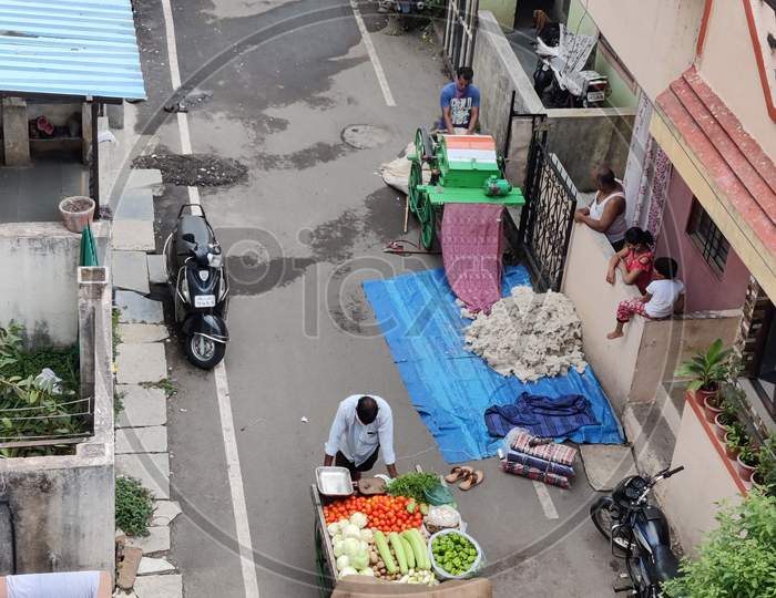Men working for daily wages. one is selling on carts and second man is making mattress