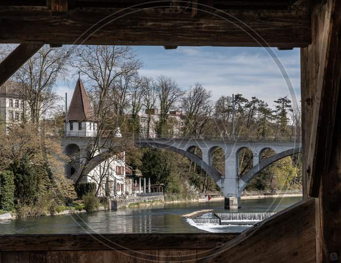 View Over Reuss River To White Tower Called Katzenturm And Rail Viaduct In Bremgarten At Springtime.
