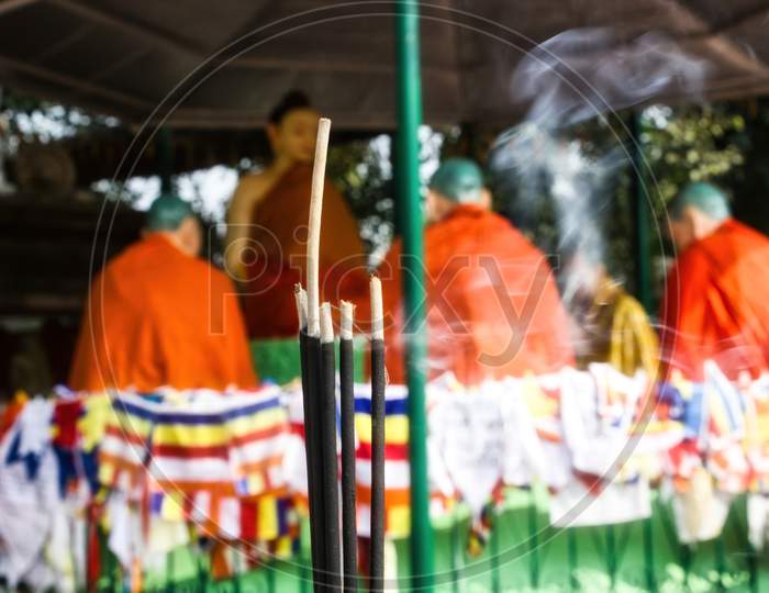 Agarbatti Translates To Incense Sticks Against Out Of Focus Idols Of Buddha And Disciples Under Sacred Bodhi Tree & Complex At Sarnath, Where Lord Buddha Delivered First Sermon After Gained Enlightenment About 2500 Years Ago.