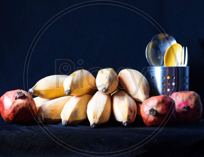 Yellow Ripe Bananas And Red Pomegranates With Cutlery