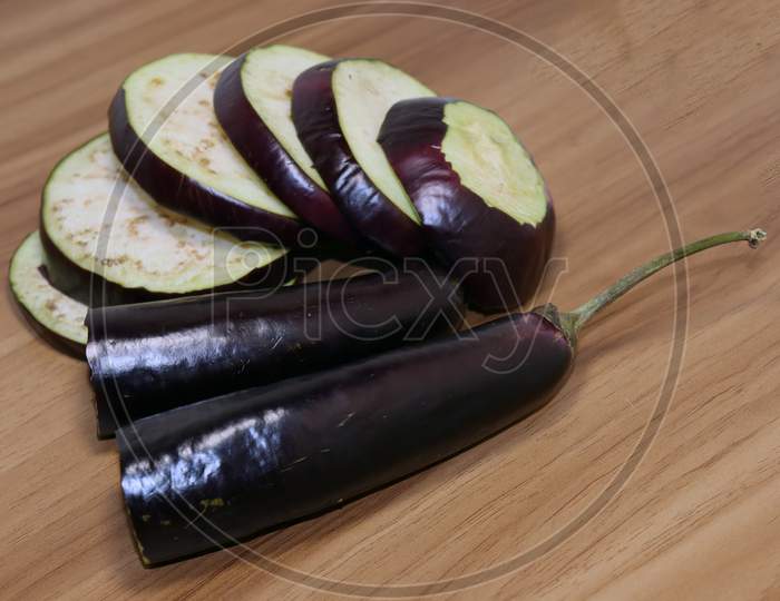 Violet Colored Brinjal On Wooden Table For Cooking