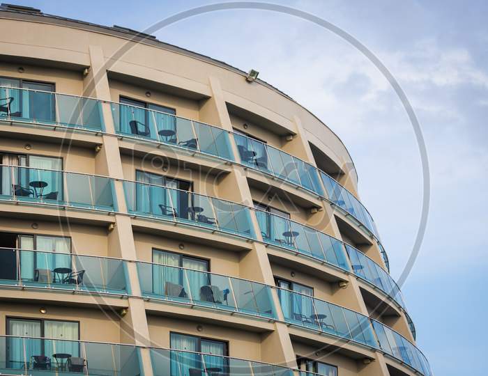 A Residential Building With Flat, Identical Balconies With Ripped Air Conditioners And  Glass. Balcony Pattern