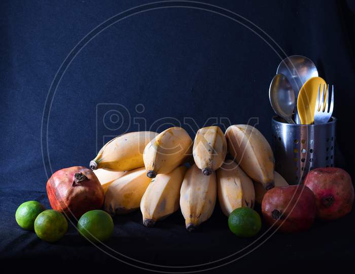 Yellow Bananas, Green Lemons And Red Pomegranates With Cutlery