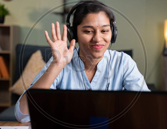 Young Business Woman On Online Meeting By Greeting Hai On Video Conference While Working From Home - Concept Of Video Chat, Conference Or Vlogging From Home By Looking At Camera.