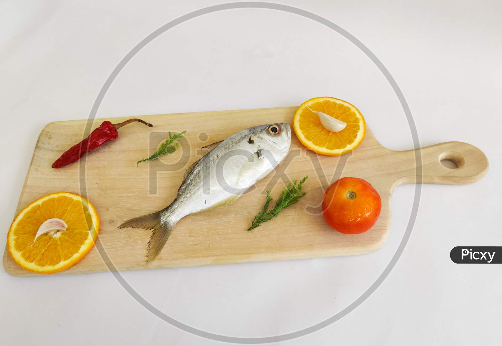 Fresh White Fish,False Trevally Decorated With Herbs And Vegetables .On A White Background,Selective Focus.