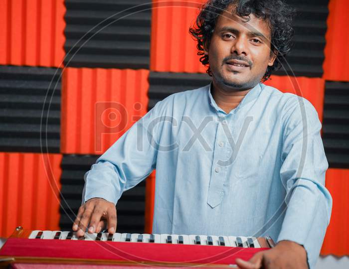 Young Man Playing Indian Music Instrument Harmonium In Recording Studio - Concept Of Hobby And Leisure Activities