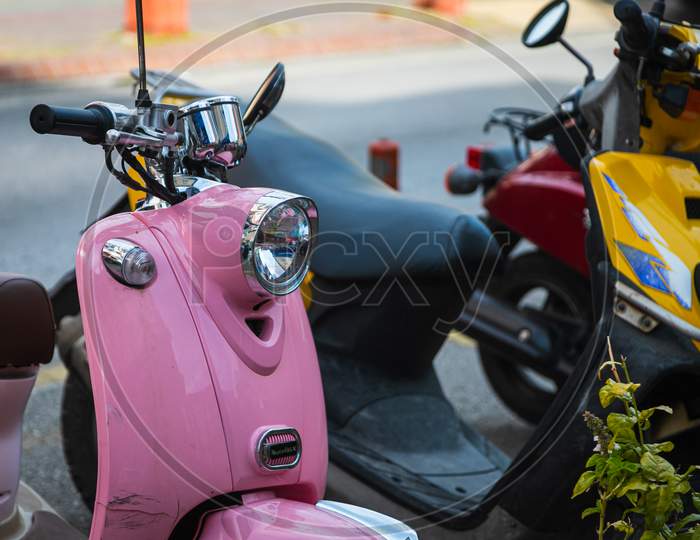 A Vintage  Pink    Motorcycle, Moped  Stands In A Parking Against The Backdrop Of  Street , Side  View
