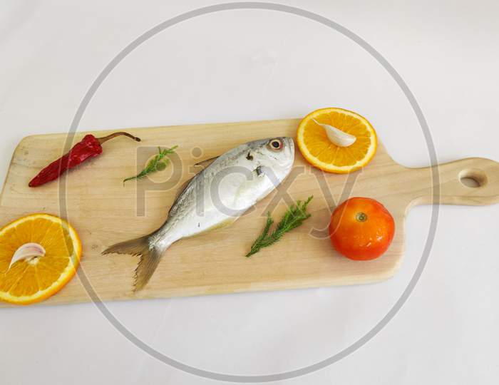 Fresh White Fish,False Trevally Decorated With Herbs And Vegetables .On A White Background,Selective Focus.