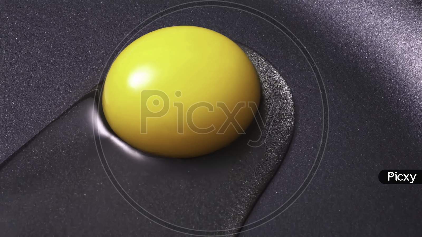 Closeup of raw yellow egg yolk on a black frying pan.