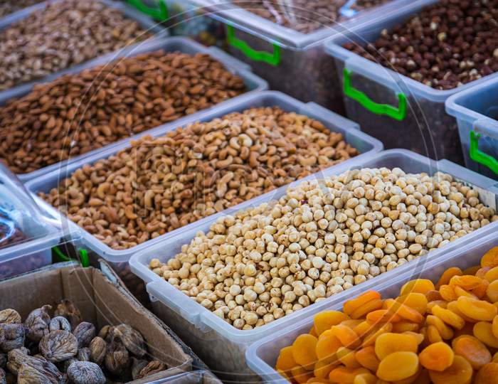 Close-Up Of Beautiful Rows Of Fresh Nuts: Shelled Hazelnuts, Cashews, Almonds, Figs, Raisins, Dried Apricots. Various Nuts On The Market Showcase, Ыщае Ащсгы