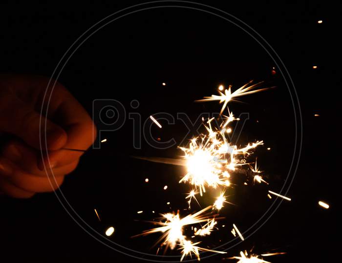 beautiful sparkler hold in the hand of a child during happy new year wishing on new years eve in the dark night with silver sparkles and a fiery glow in the night