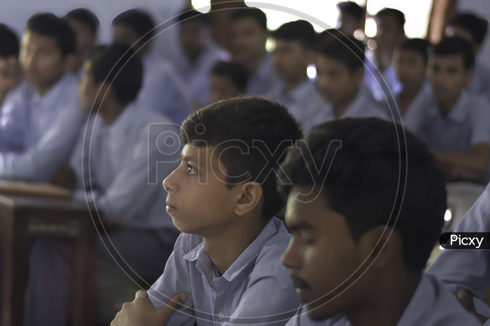 Group of Indian Government school boys students in uniform looking towards blackboard in the classroom of their school. Asian Students studying inside classroom.