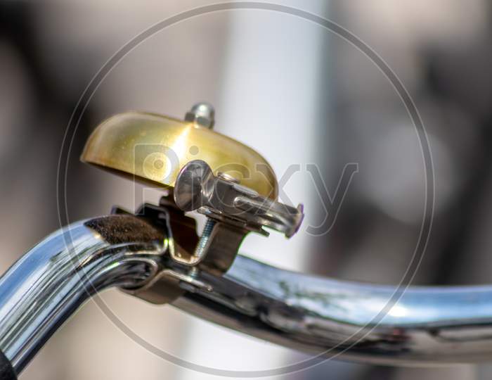 Beautiful bike bell with a shiny finish at a silver metal bicycle handlebar as sustainable mobility and a lot of copy space and a blurred background shows safety aspects and emission free transportation