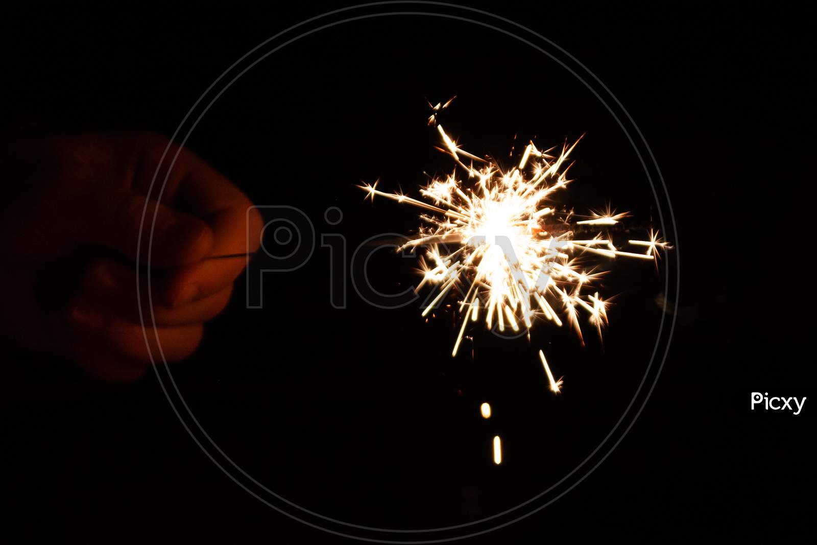 beautiful sparkler hold in the hand of a child during happy new year wishing on new years eve in the dark night with silver sparkles and a fiery glow in the night