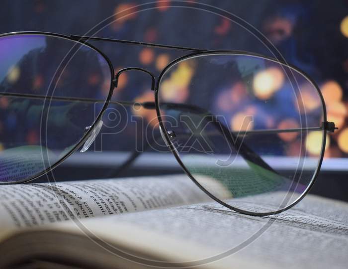 glasses on book with lights in background