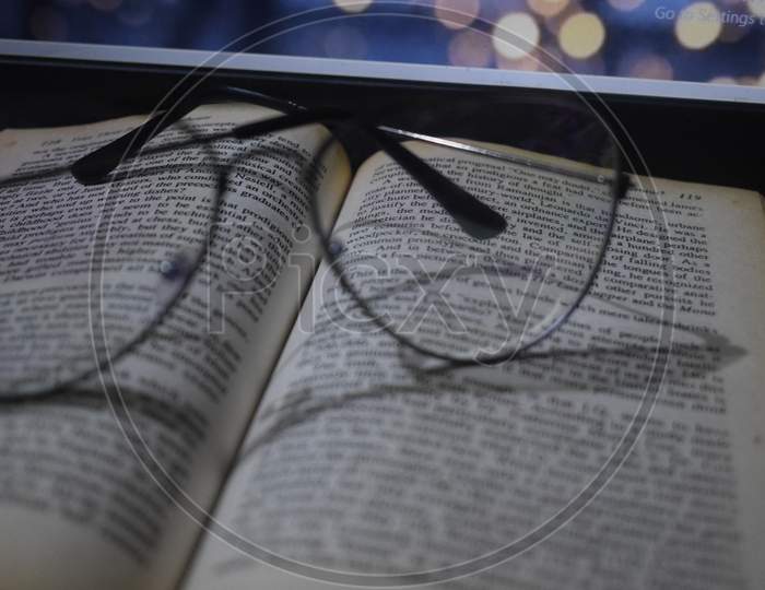 Glasses on book with laptop in background