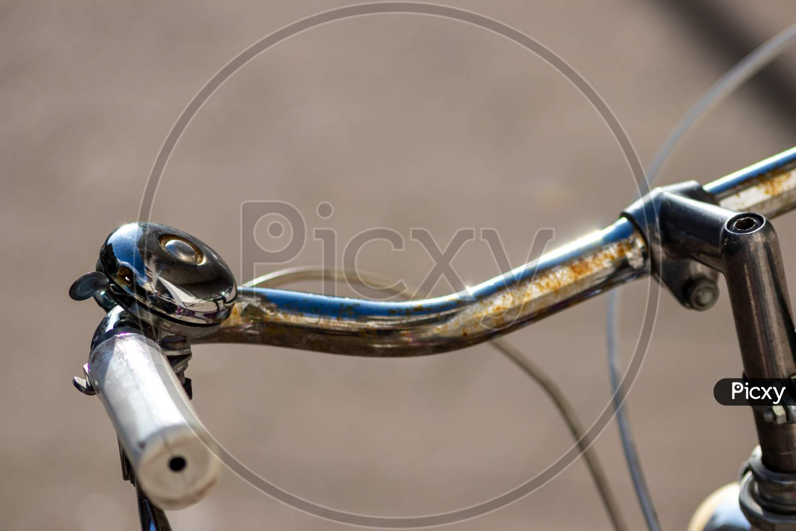 Beautiful bike bell with a shiny finish at a silver metal bicycle handlebar with a black grip and a lot of copy space and a blurred background shows safety aspects and emission free transportation