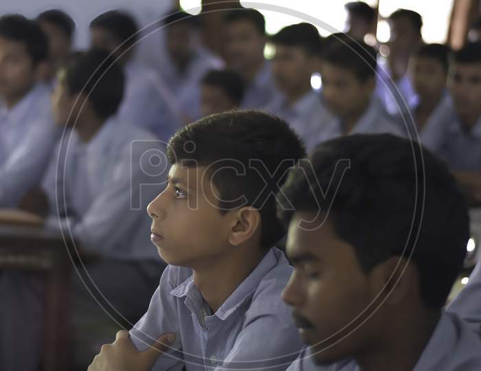Group of Indian Government school boys students in uniform looking towards blackboard in the classroom of their school. Asian Students studying inside classroom.