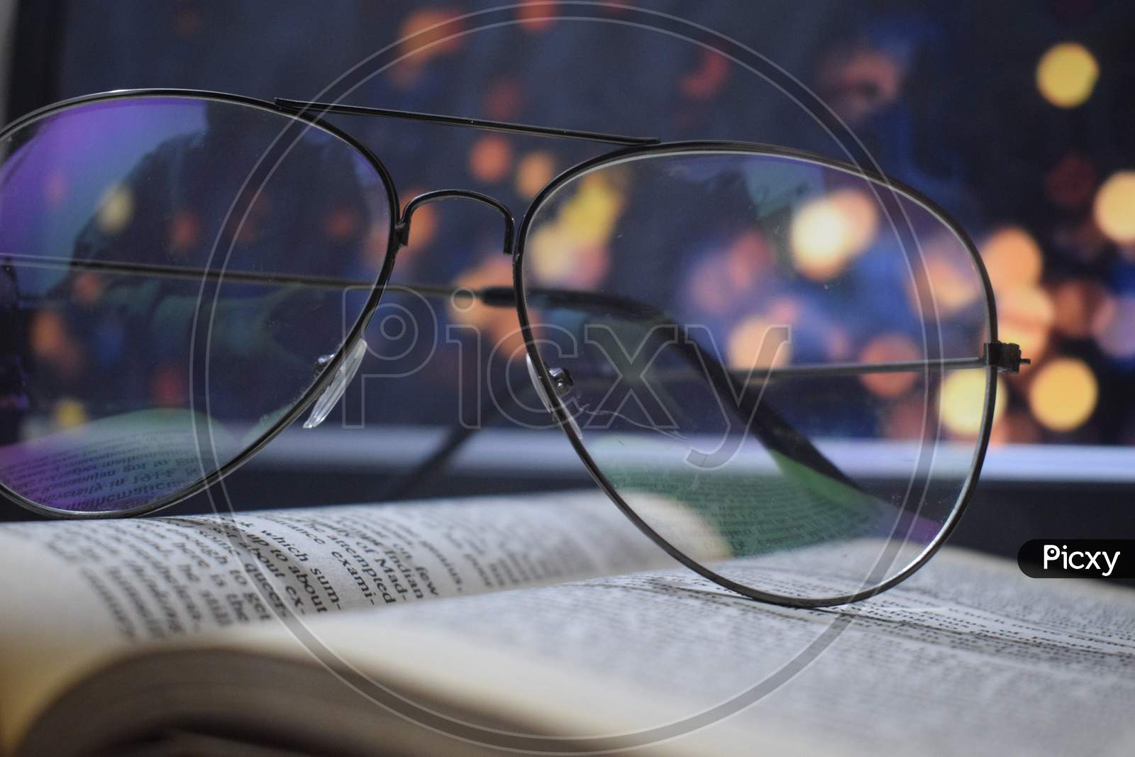 glasses on book with lights in background