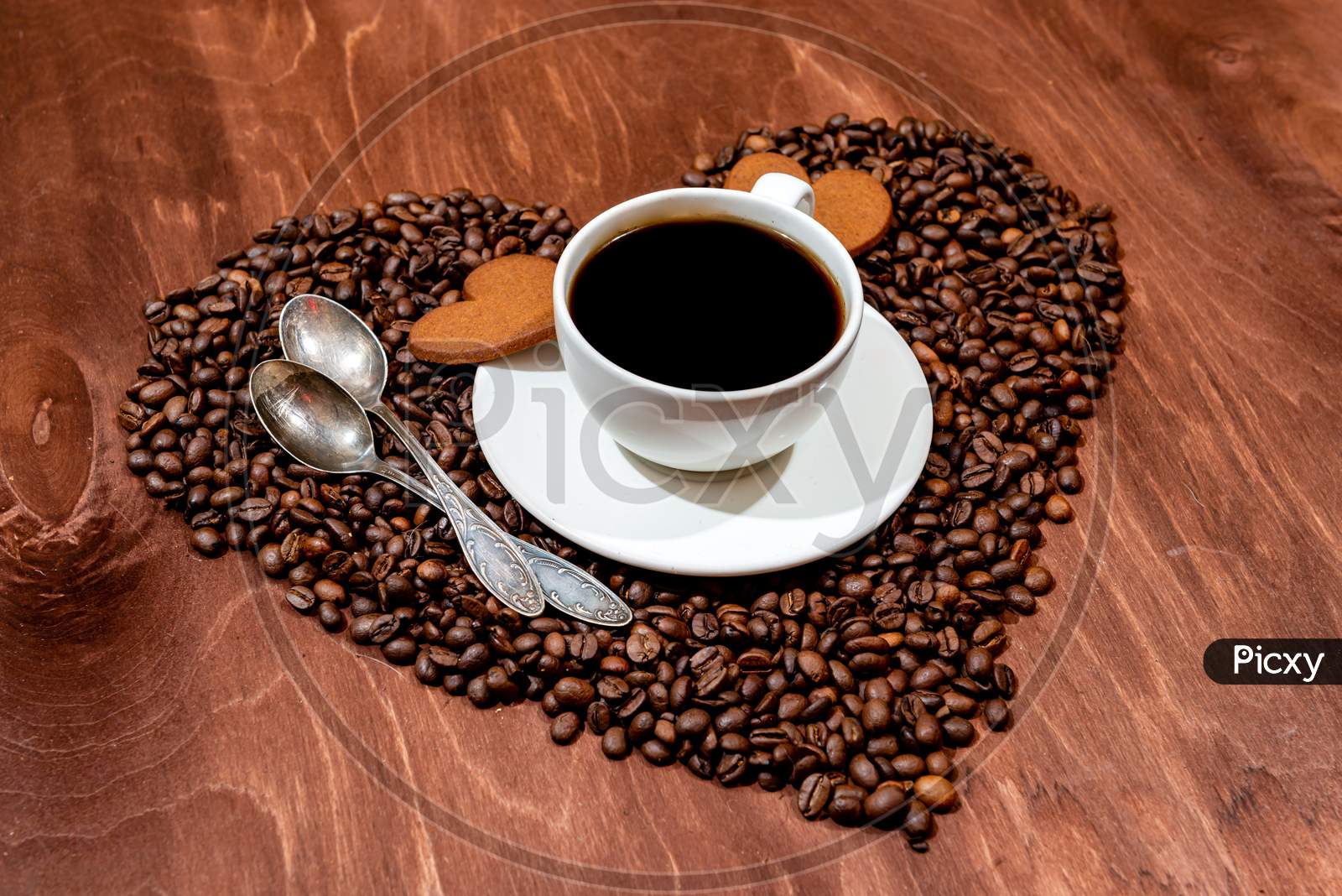 White Coffee Mug, Heart Shaped Gingerbread And Two Spoons On A Heart Shaped Base Made From Coffee Beans