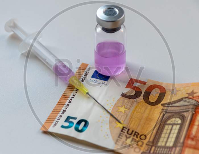 Health care costs for medicine and therapy drugs with injection needles and medicine ampullas stand beside european bank notes and euro coins to show medical expenses and medical research