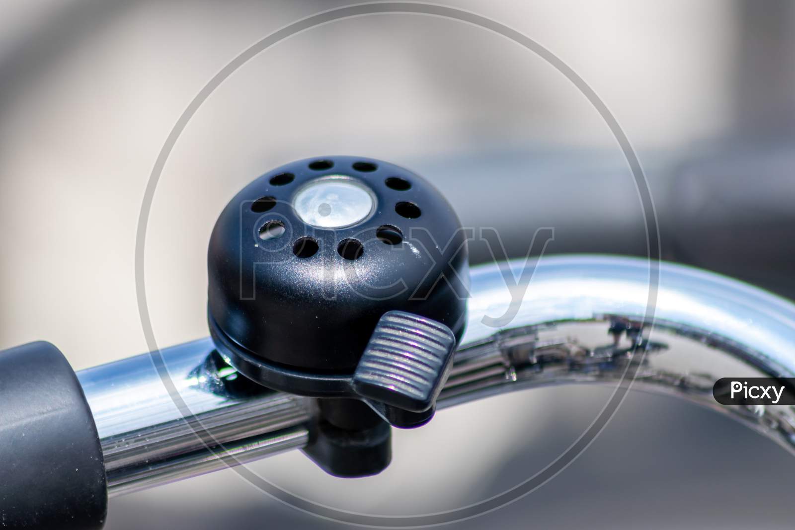 Beautiful bike bell with a shiny finish at a silver metal bicycle handlebar as sustainable mobility and a lot of copy space and a blurred background shows safety aspects and emission free transportation