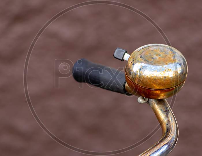 Beautiful bike bell with a shiny finish at a silver metal bicycle handlebar with a black grip and a lot of copy space and a blurred background shows safety aspects and emission free transportation