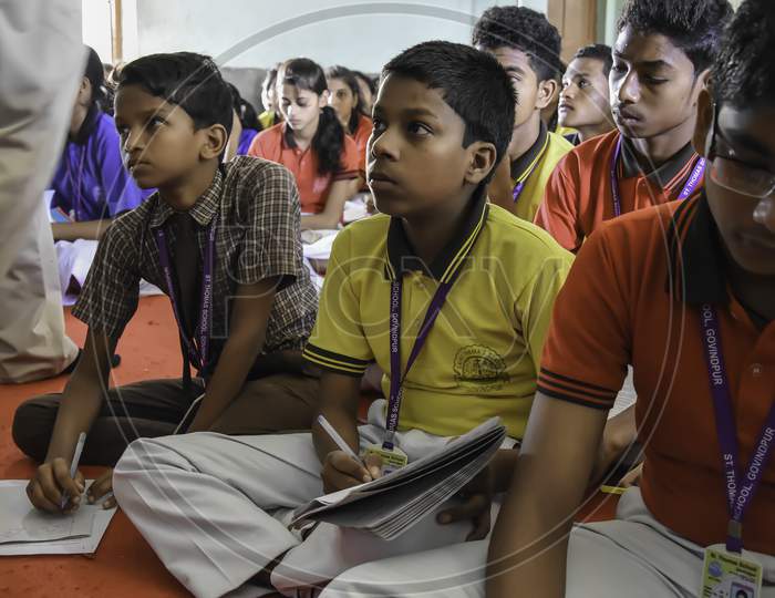 Group of unidentified Indian school students of government school sitting on floor during class activity. Focused on studies