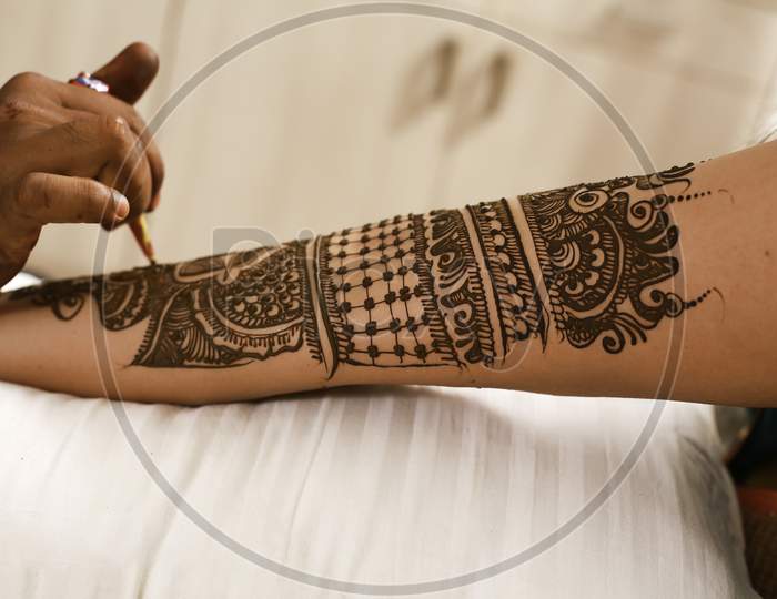 tattooed by hand with hena. Drawing process of henna menhdi ornament on woman's hand