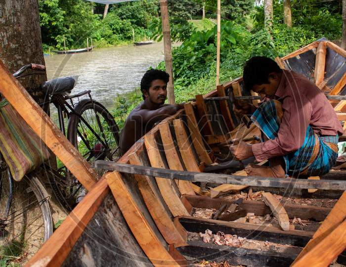 Pangsha-Rajbari, Bangladesh - 6 July 2020 Two People Are Building A New Wooden Boat On The Banks Of The River Chatra. It Is A Tributary Of The Kushtia Gorai River.