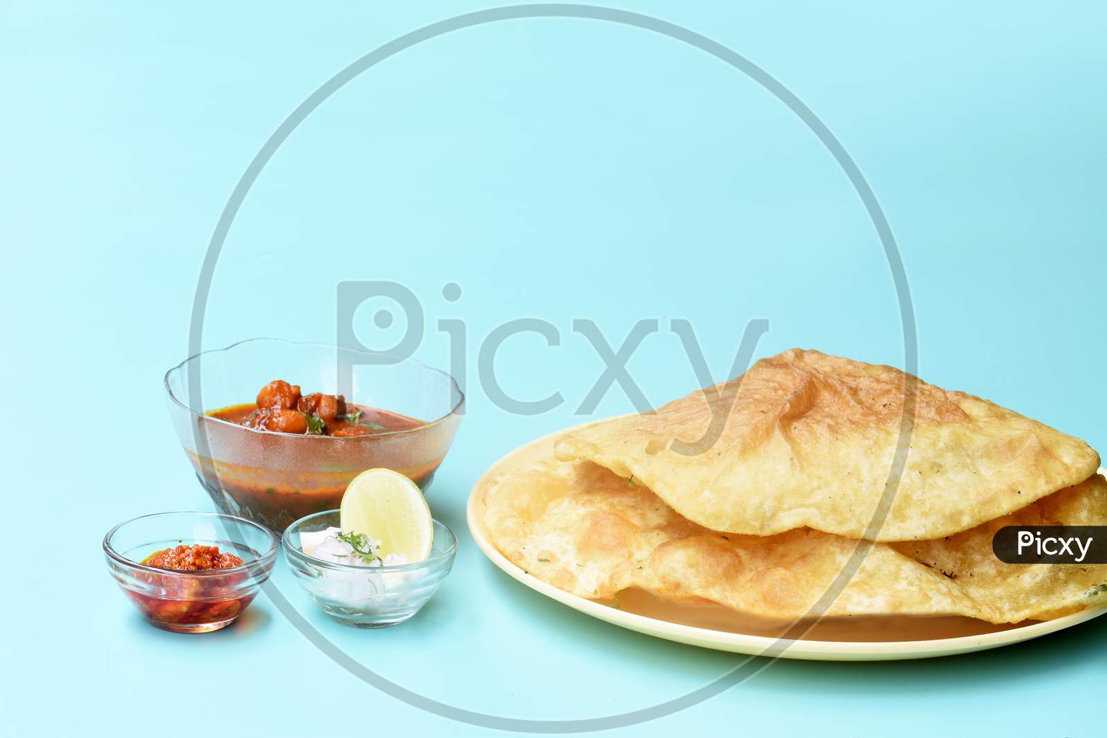 Indian Dish Spicy Chick Peas Curry Also Known As Chole Bhatura And Chana Masala Or Chole Or Chickpeas Masala Curry,Traditional North Indian Lunch Served With Fried Puri Or Flatbreads,Selective Focus
