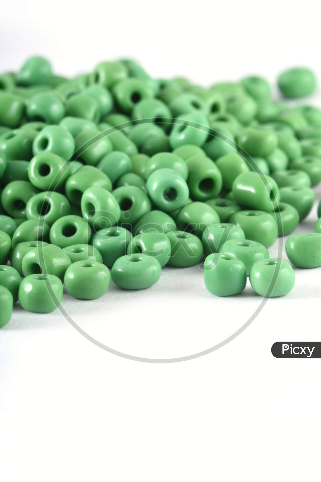Close Up Of Green Beads On The White Background. Background Or Texture Of Beads. Macro,It Is Used In Finishing Fashion Clothes. Make Bead Necklace Or String Of Beads For Woman Of Fashion.