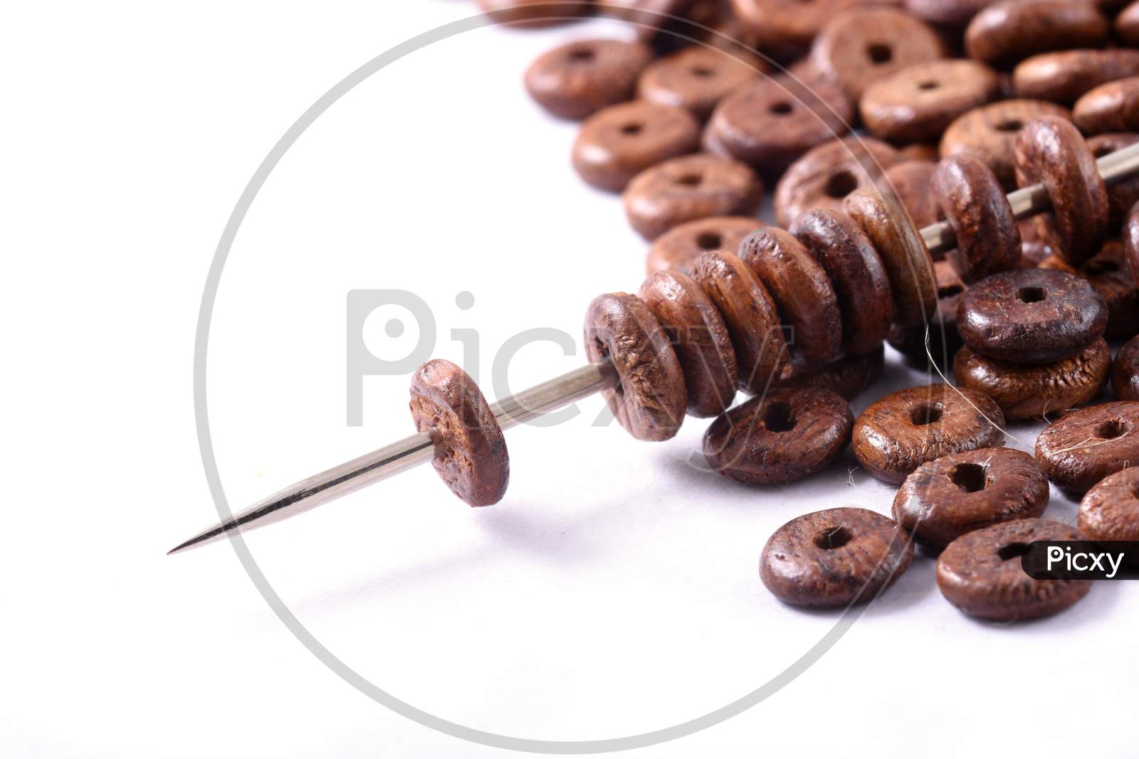 Wooden Beads Spread On White Background With Needle. Beads With Needle . Close Up, Macro.