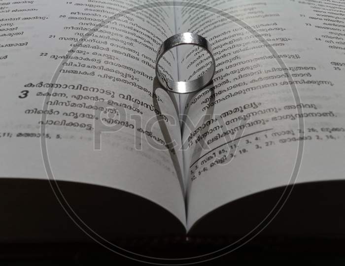 A ring ,heart symbol on a book - image