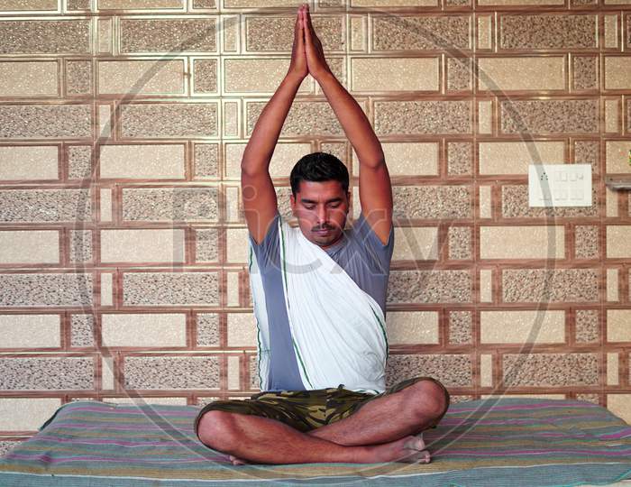 Young Indian Sitting In Yoga Position And Meditating At Home. Worldwide Yoga Day Concept.