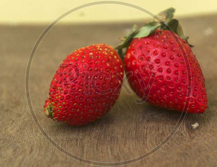 Two Red Strawberries On A Wooden Surface