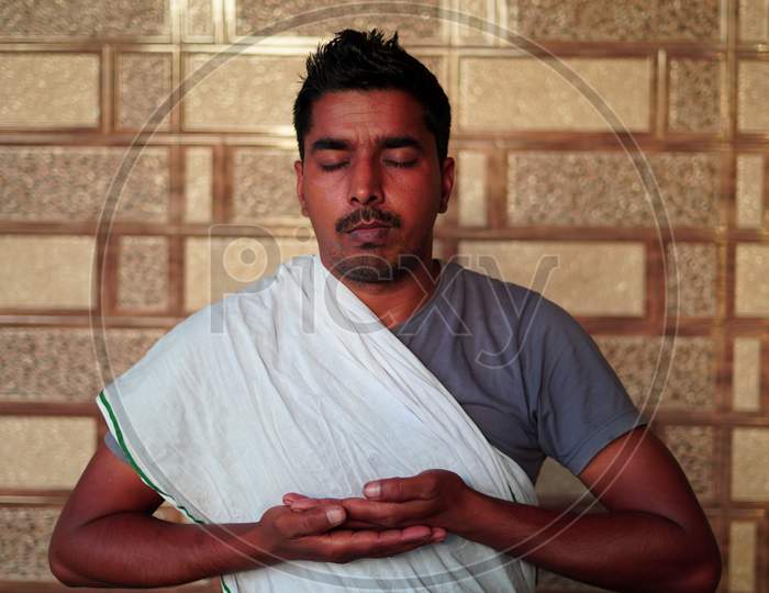 Young Indian Man Sitting In Yoga Position And Meditating At Home. Worldwide Yoga Day Concept.