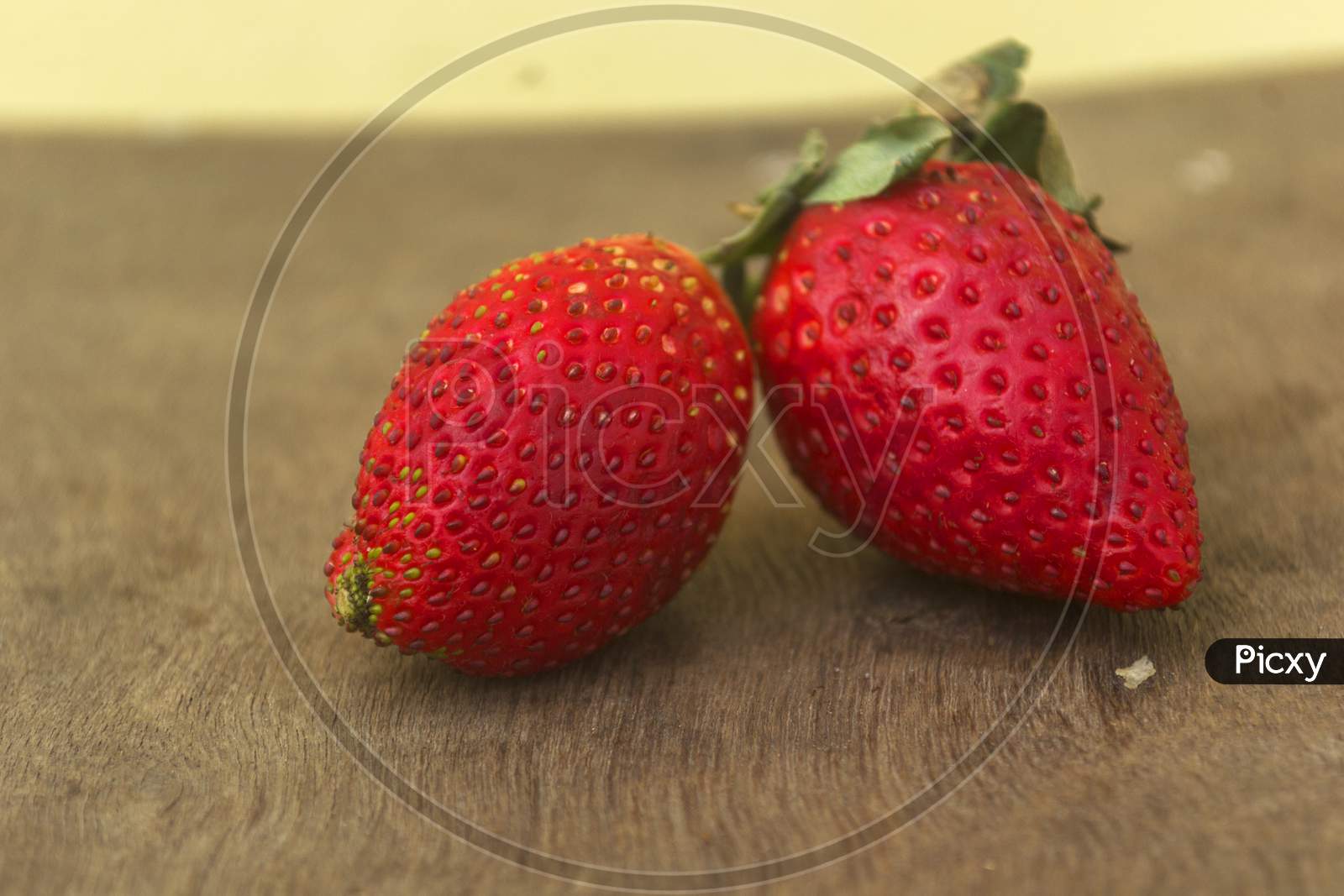 Two Red Strawberries On A Wooden Surface