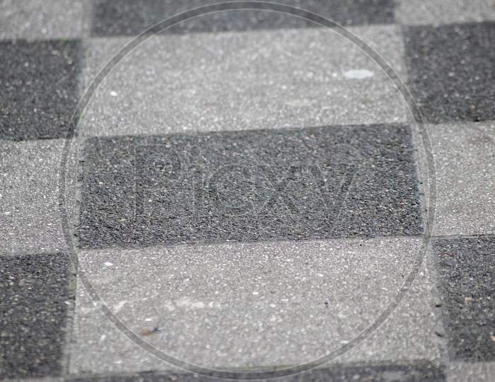 Chessboard pattern in waiting area on sidewalk pavement shows black and white checkerboard texture in rhombuses and geometric shapes background with black tiles and white tiles classic design surface