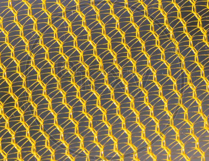 Yellow mesh structure in close-up with backlight on shine morning shows abstract pattern of seamless material textured in golden light as graphical element for backdrop wallpaper and fabric macro