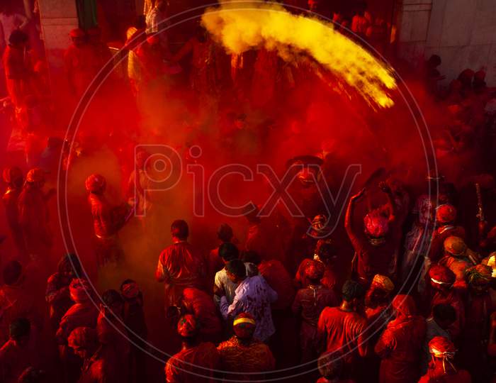 Indian people gathered in a temple and playing holi with colourful powder