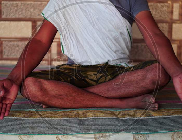 Attractive Young Indian Man Sitting In Yoga Position And Meditating At Home. Worldwide Yoga Day Concept.