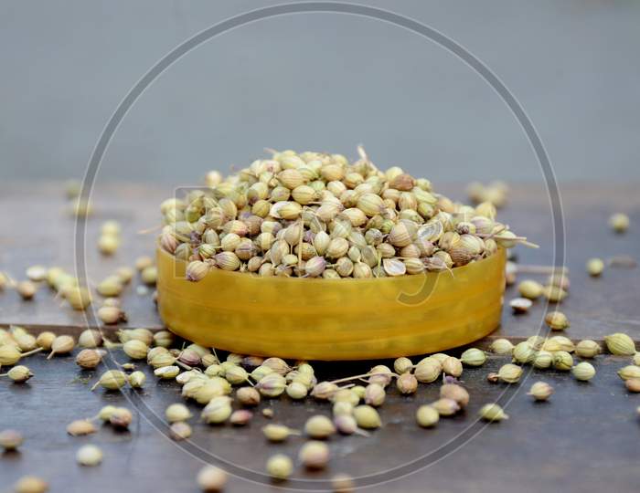 Closeup Bunch The Ripe Brown Coriander Seeds In The Plastic Bowl Over Out Of Focus Wooden Brown Background.