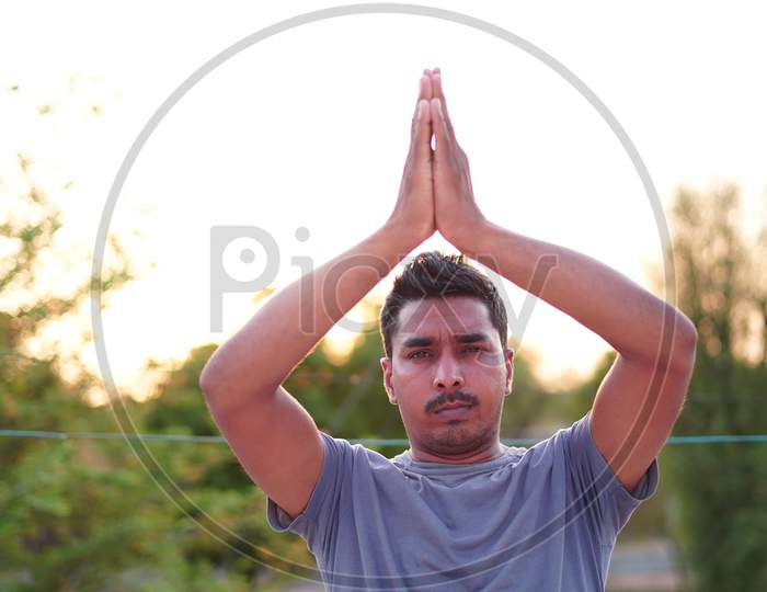 Healthy Young Man Doing Stretching Exercise On Green Grass At Park. Yoga Day Concept