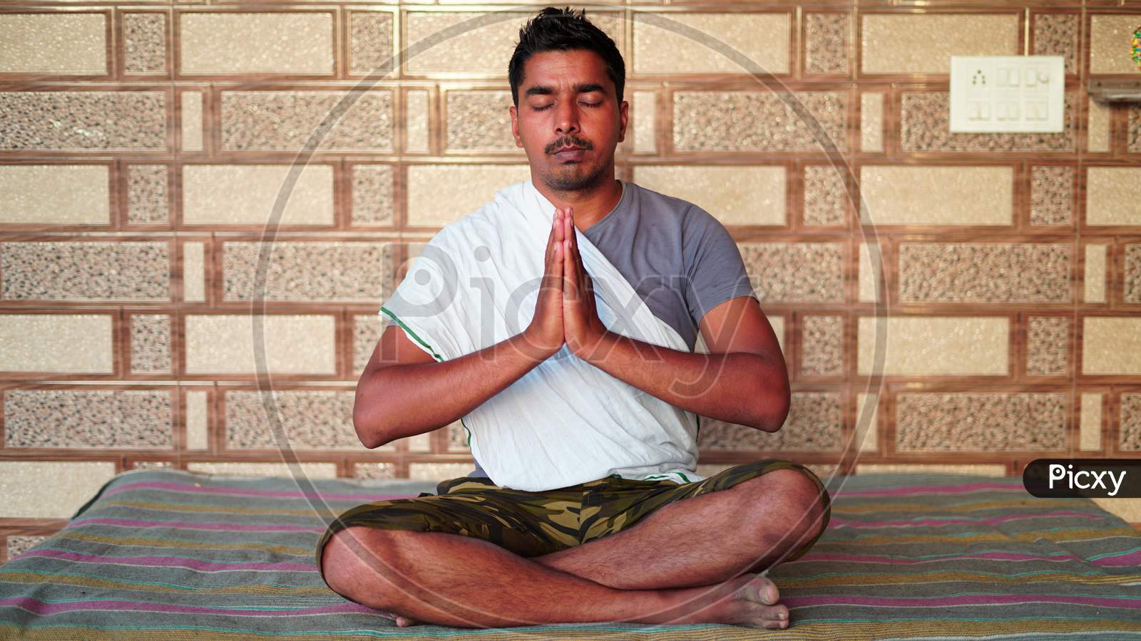 Young Asian Man Sitting In Yoga Position And Meditating At Home. Worldwide Yoga Day Concept.