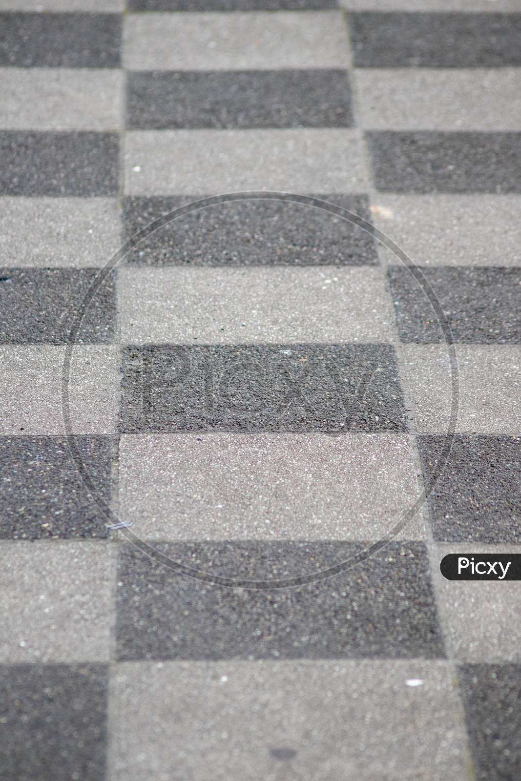 Chessboard pattern in waiting area on sidewalk pavement shows black and white checkerboard texture in rhombuses and geometric shapes background with black tiles and white tiles classic design surface
